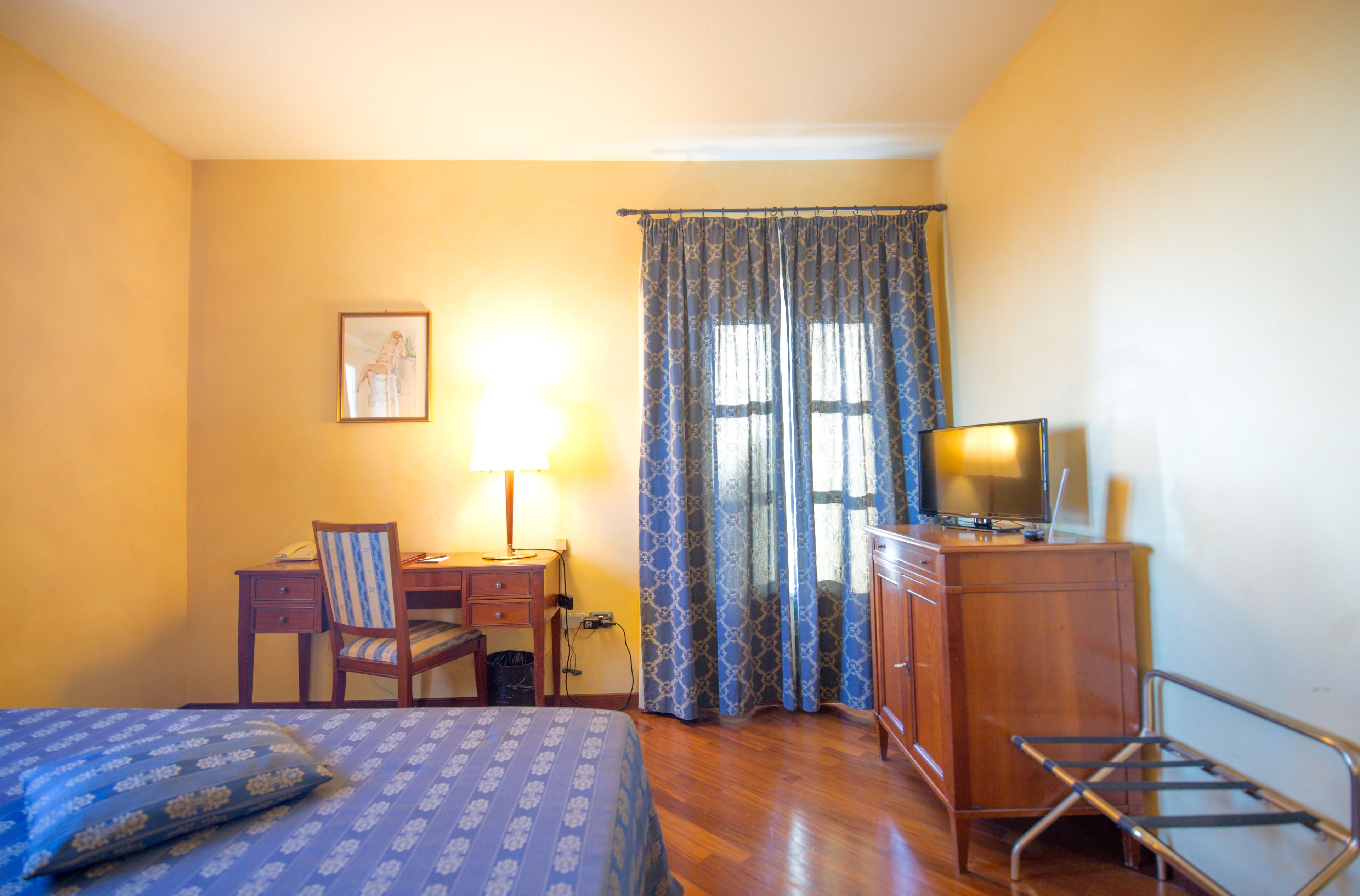 Une chambre d’hôtel équipée d’un lit, d’un bureau, d’une chaise, d’une télévision et de rideaux.