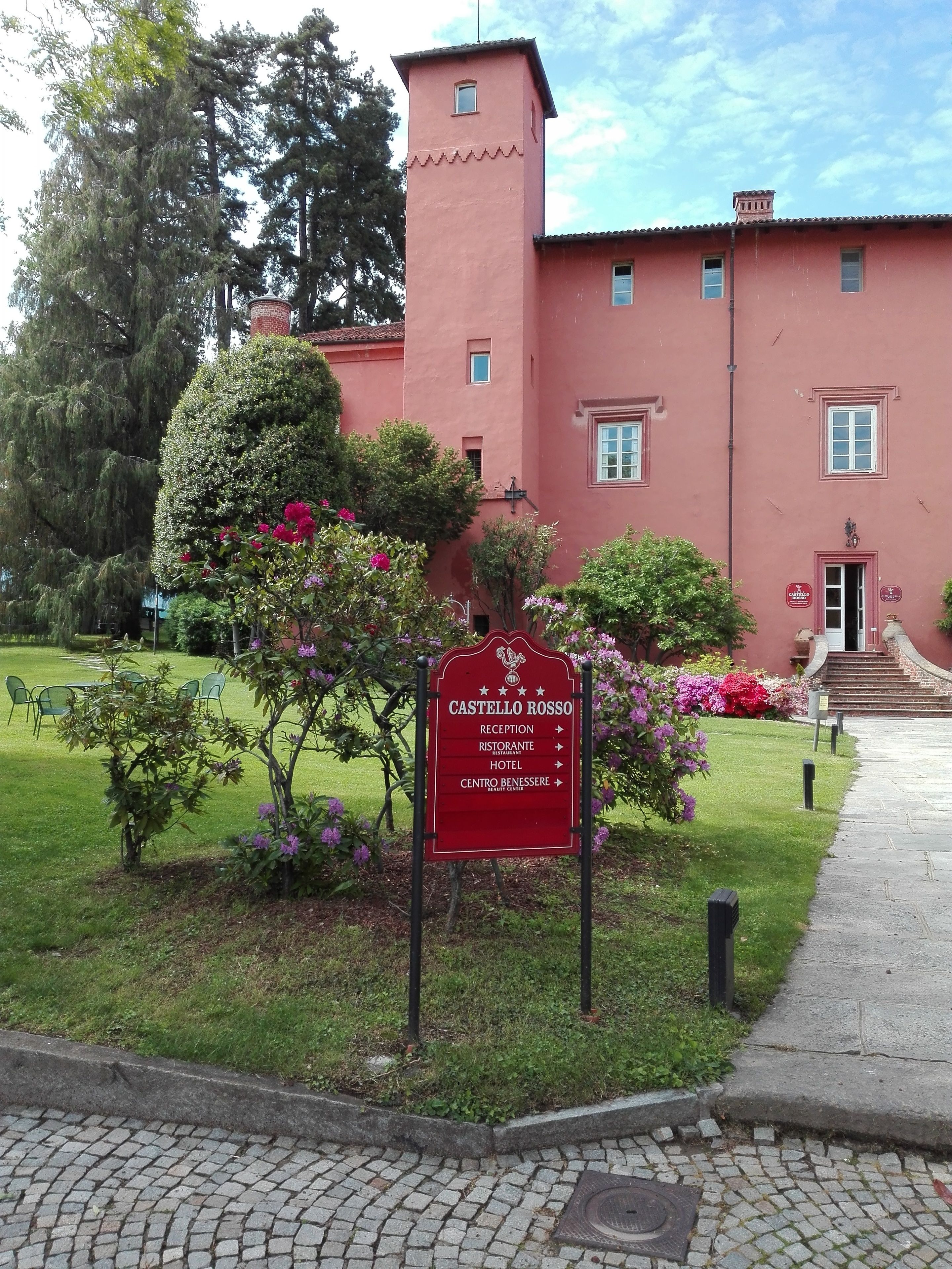 A red sign with directions to the reception, restaurant, hotel, and beauty center of Castello Rosso.