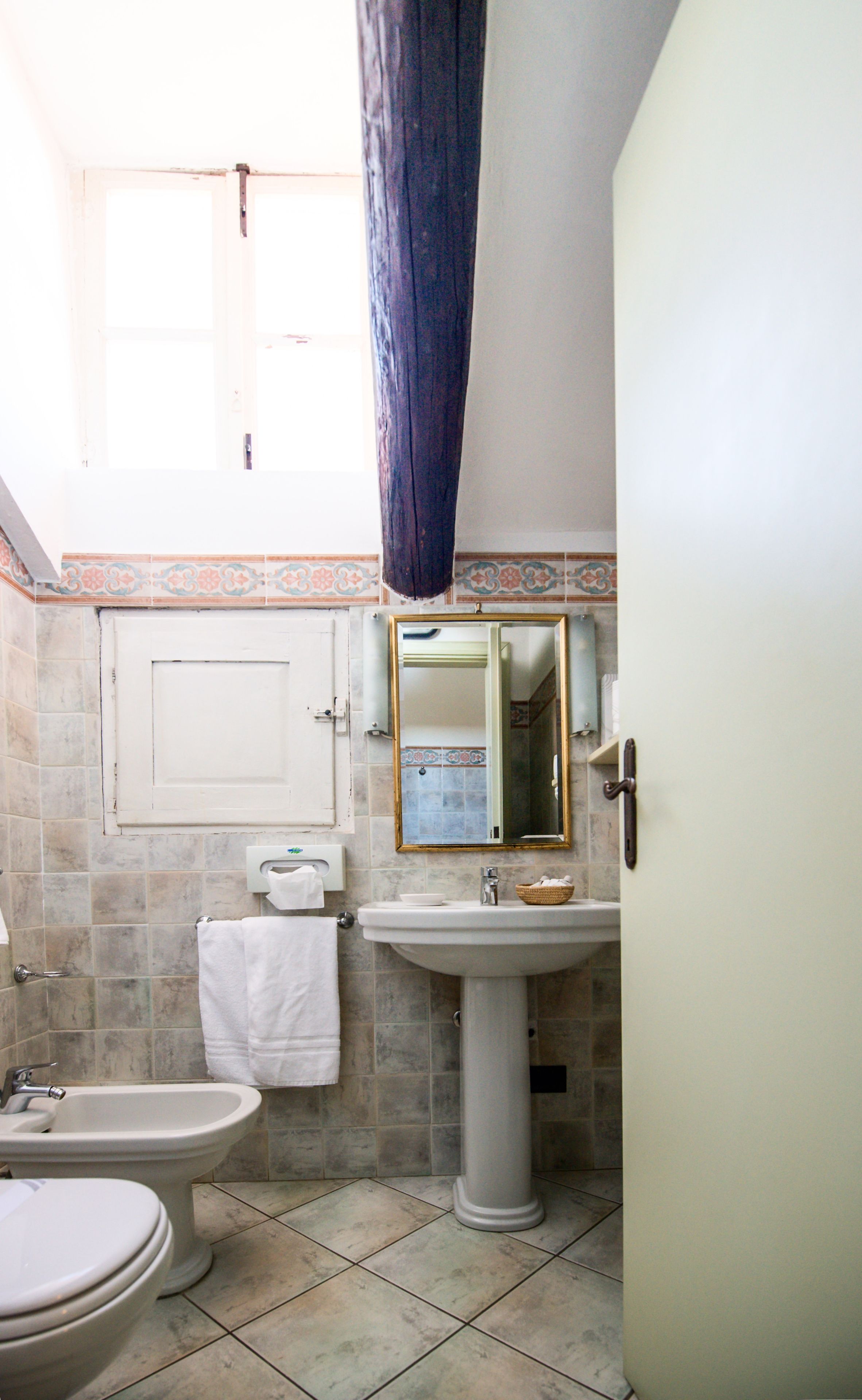 A bathroom with a pedestal sink, a bidet, a toilet, and a mirror.