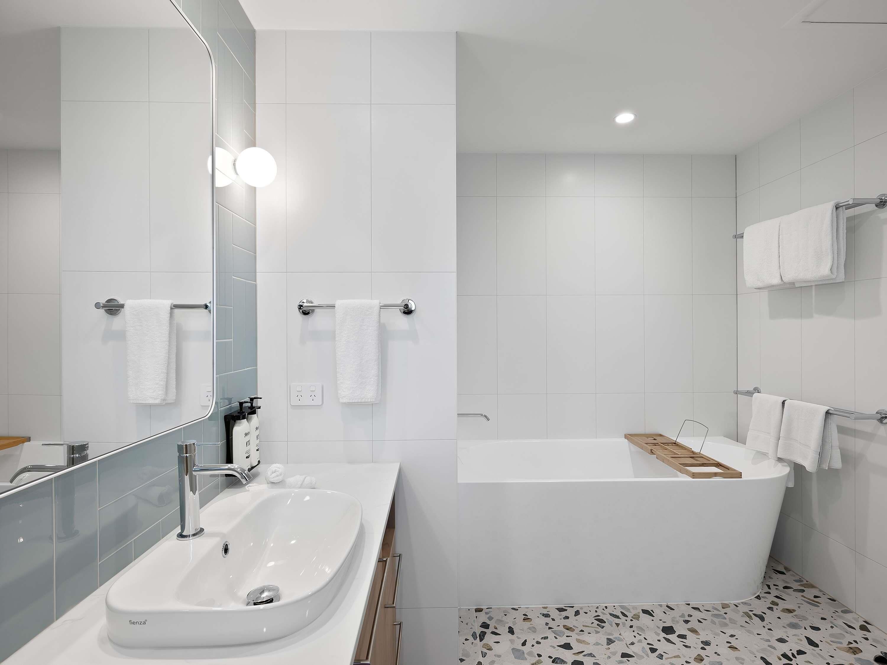 Un baño moderno con lavamanos blanco, bañera y zona de ducha.