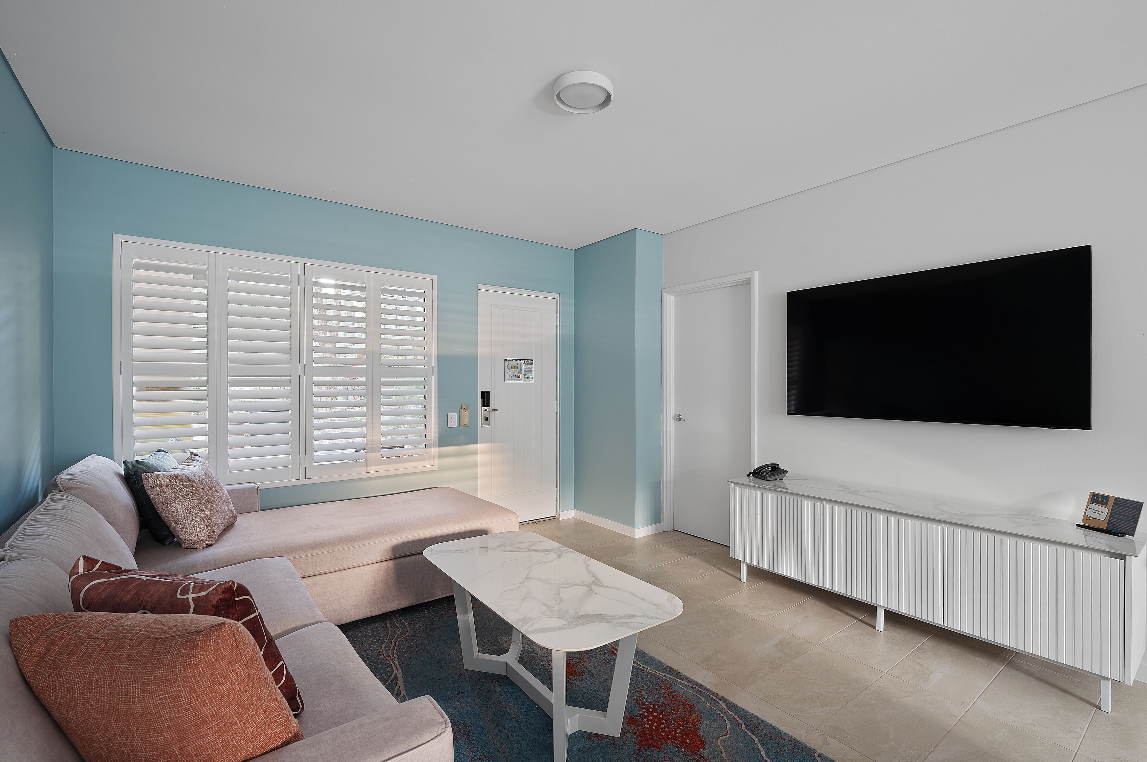 A living room with a sofa, a coffee table, a TV, and a radiator.