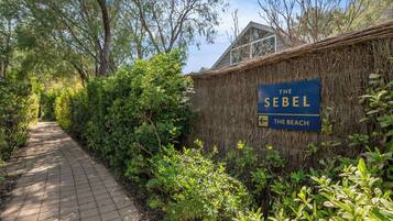 Un camino que lleva a un edificio con un letrero que dice "The Sebel The Beach".