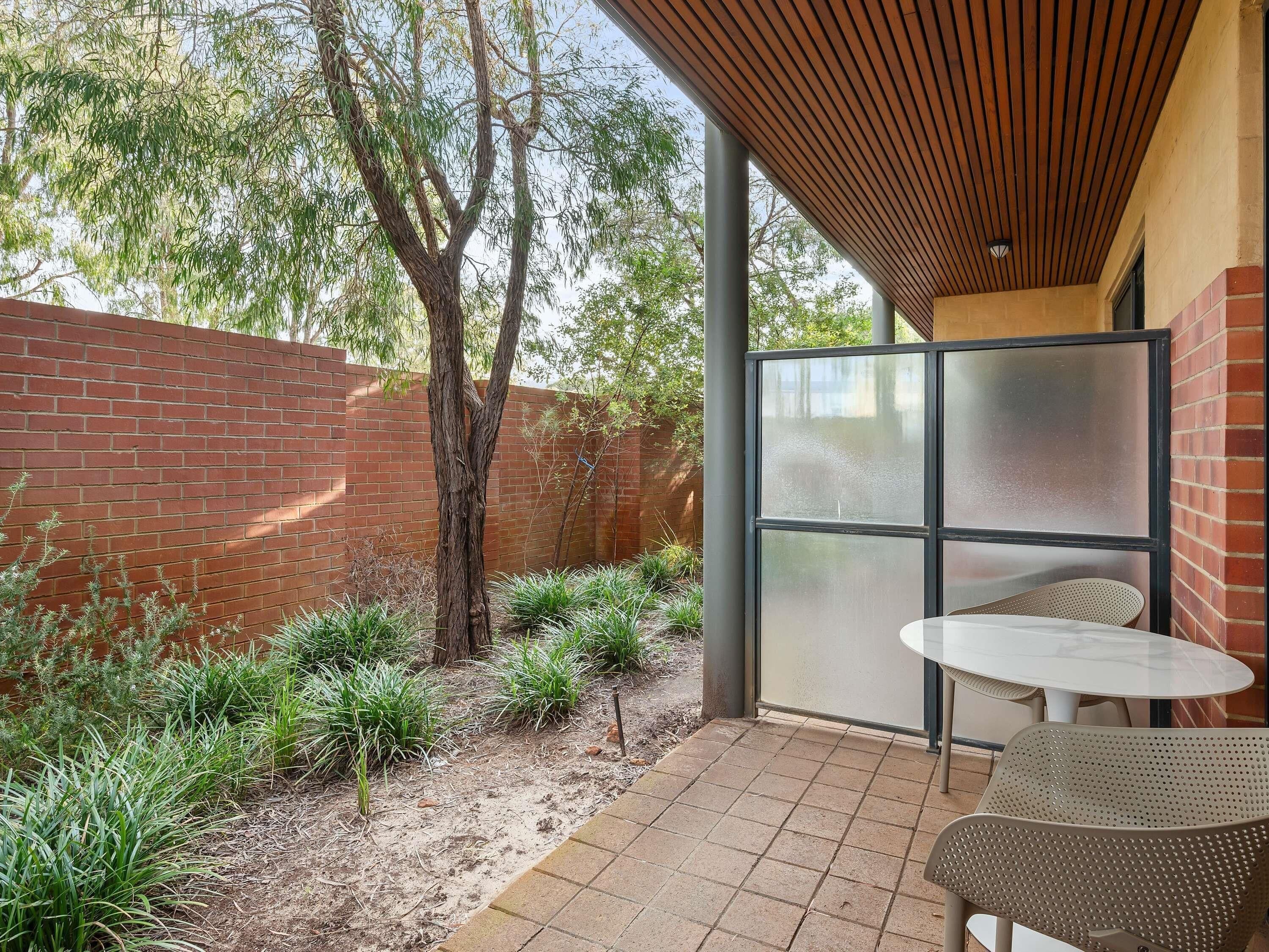 Un espace extérieur aménagé avec une table et des chaises, un mur en briques et un arbre.