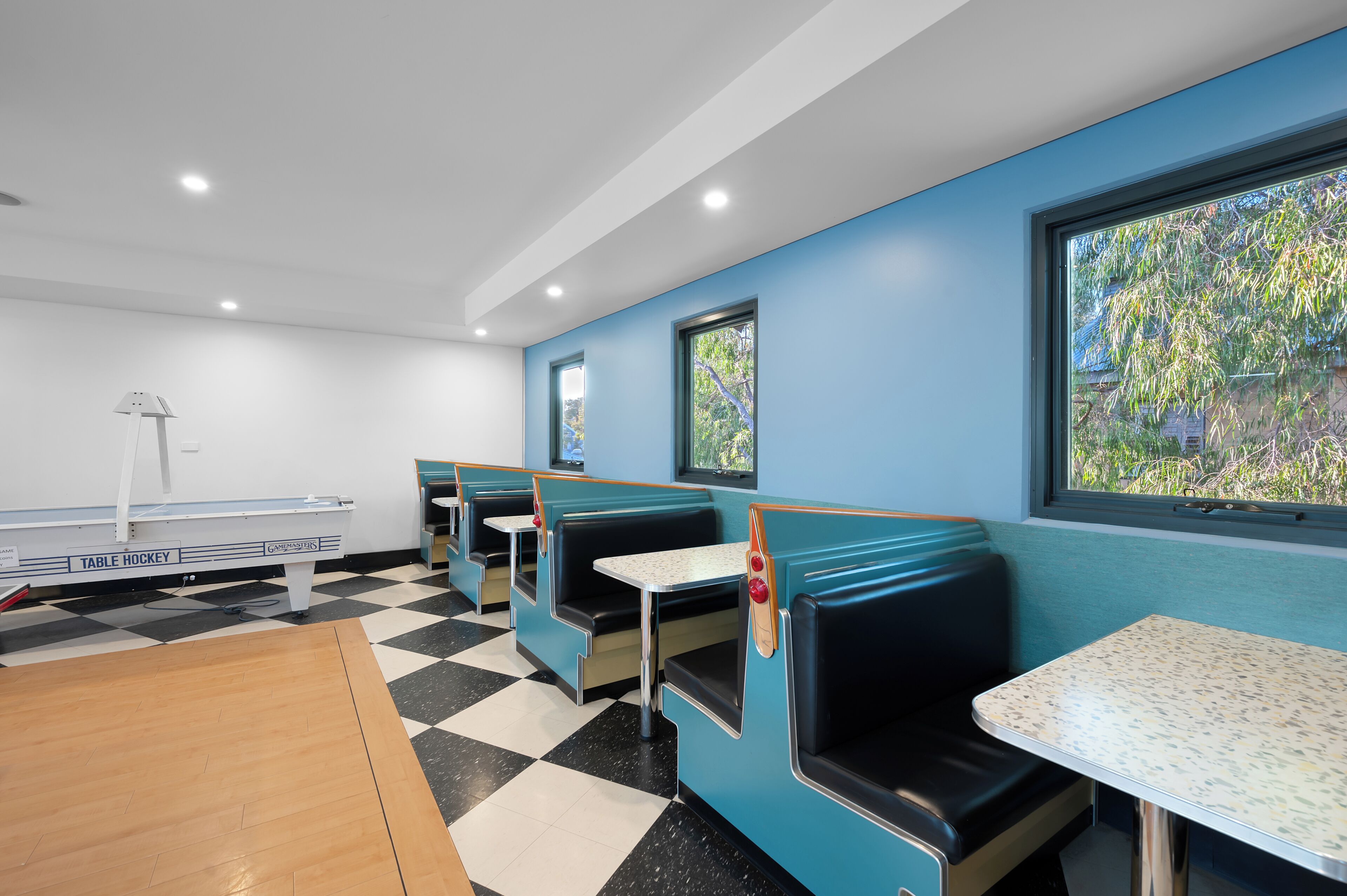 A diner with booth seating, a table hockey table, and a view of trees through the window.
