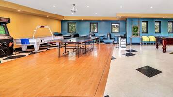 Una sala de billar con varias mesas, una mesa de billar y una mesa de ping pong.