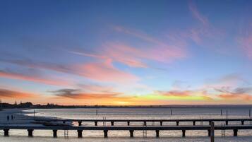 A pier extending into a calm body of water with a sunset in the background.