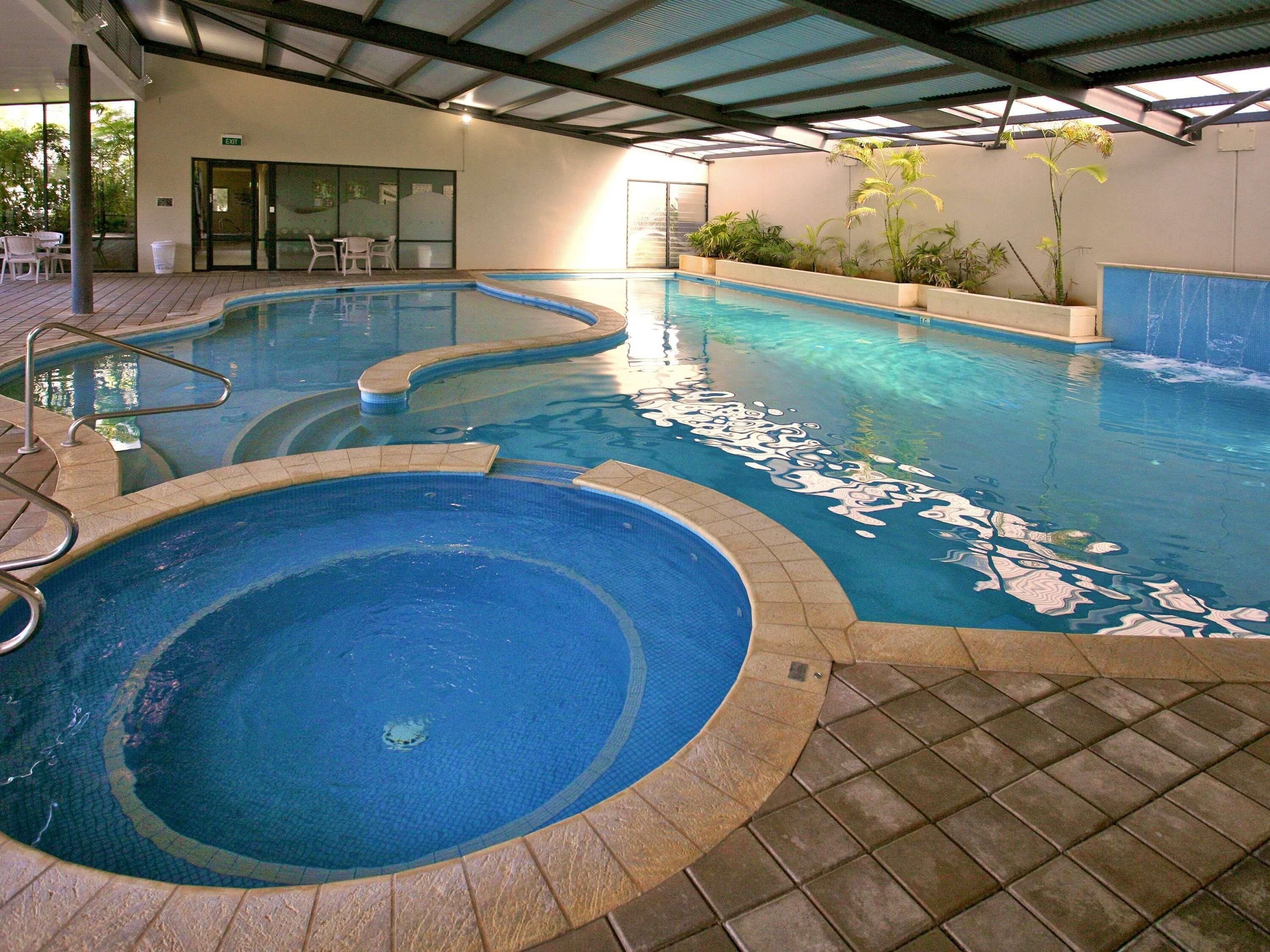 Una piscina con dos zonas separadas, una techada y un edificio con un letrero de salida.