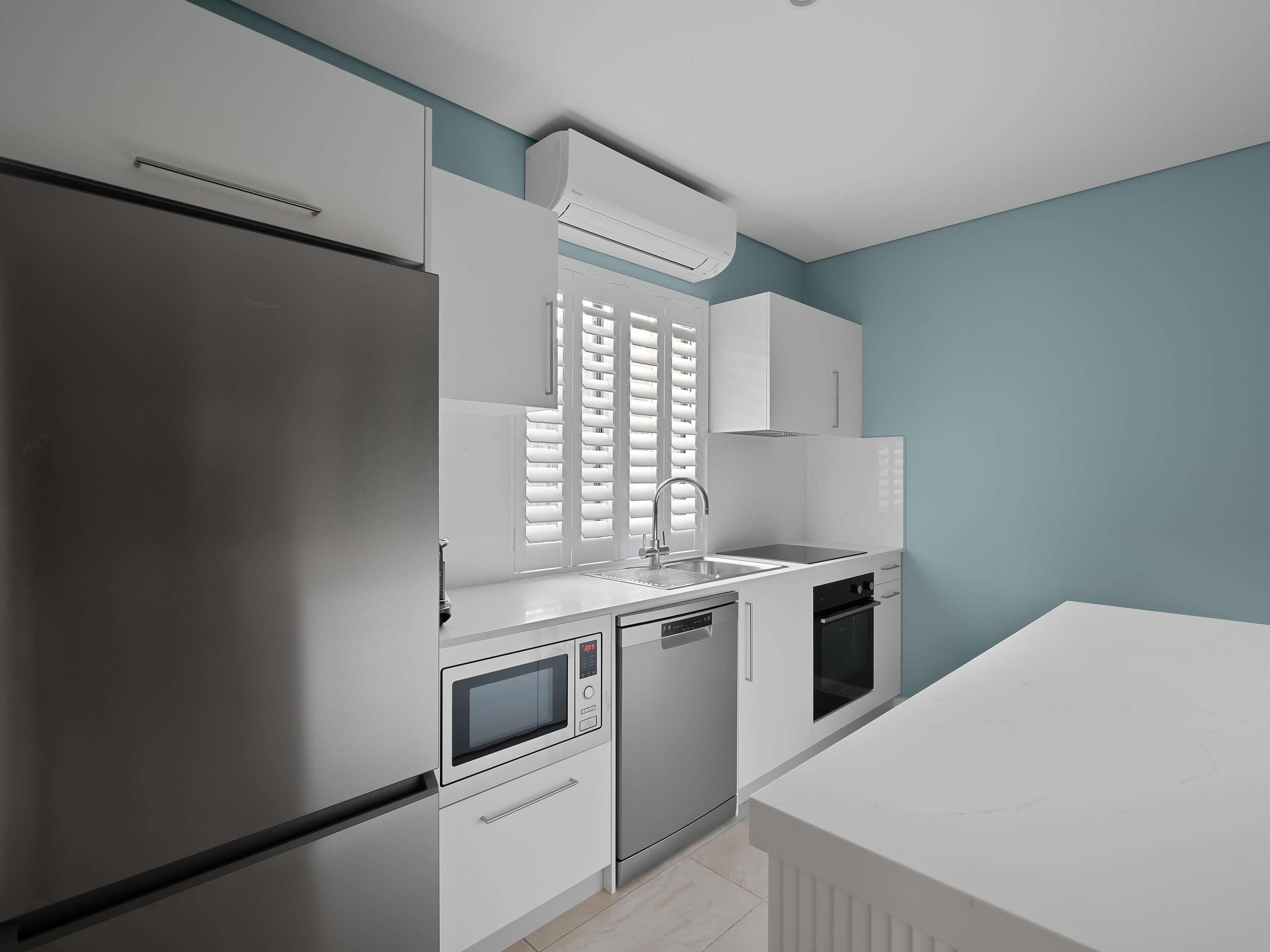 A modern kitchen with a refrigerator, microwave, oven, and sink.