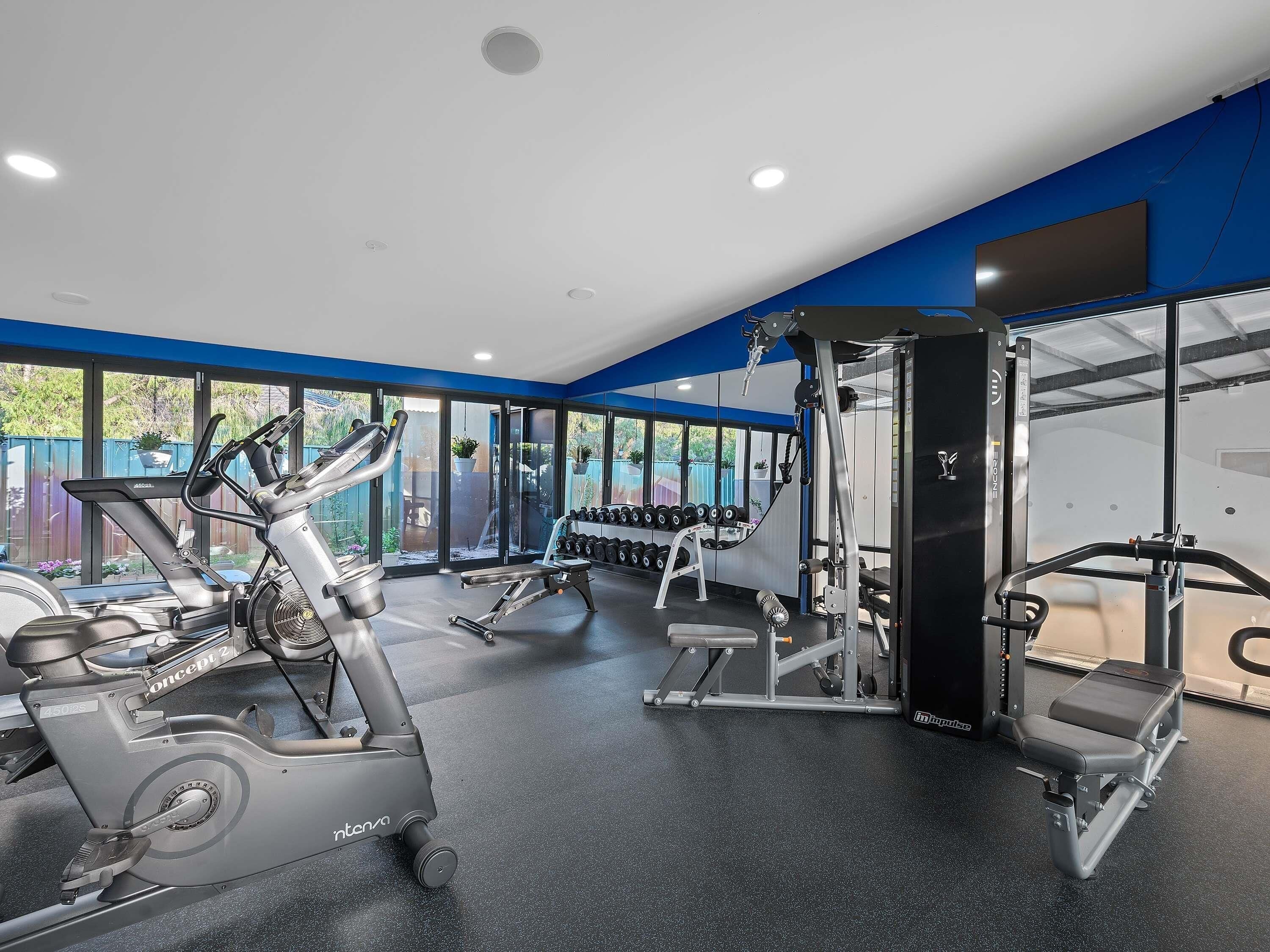 A gym with cardio equipment, weight machines, and dumbbells.
