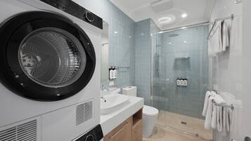 A modern bathroom with a built-in washer and dryer, a glass shower enclosure, and a toilet.