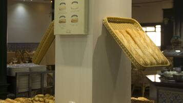 En bageridisplay med forskellige brød og kager, en menutavle og en loftsvifte.