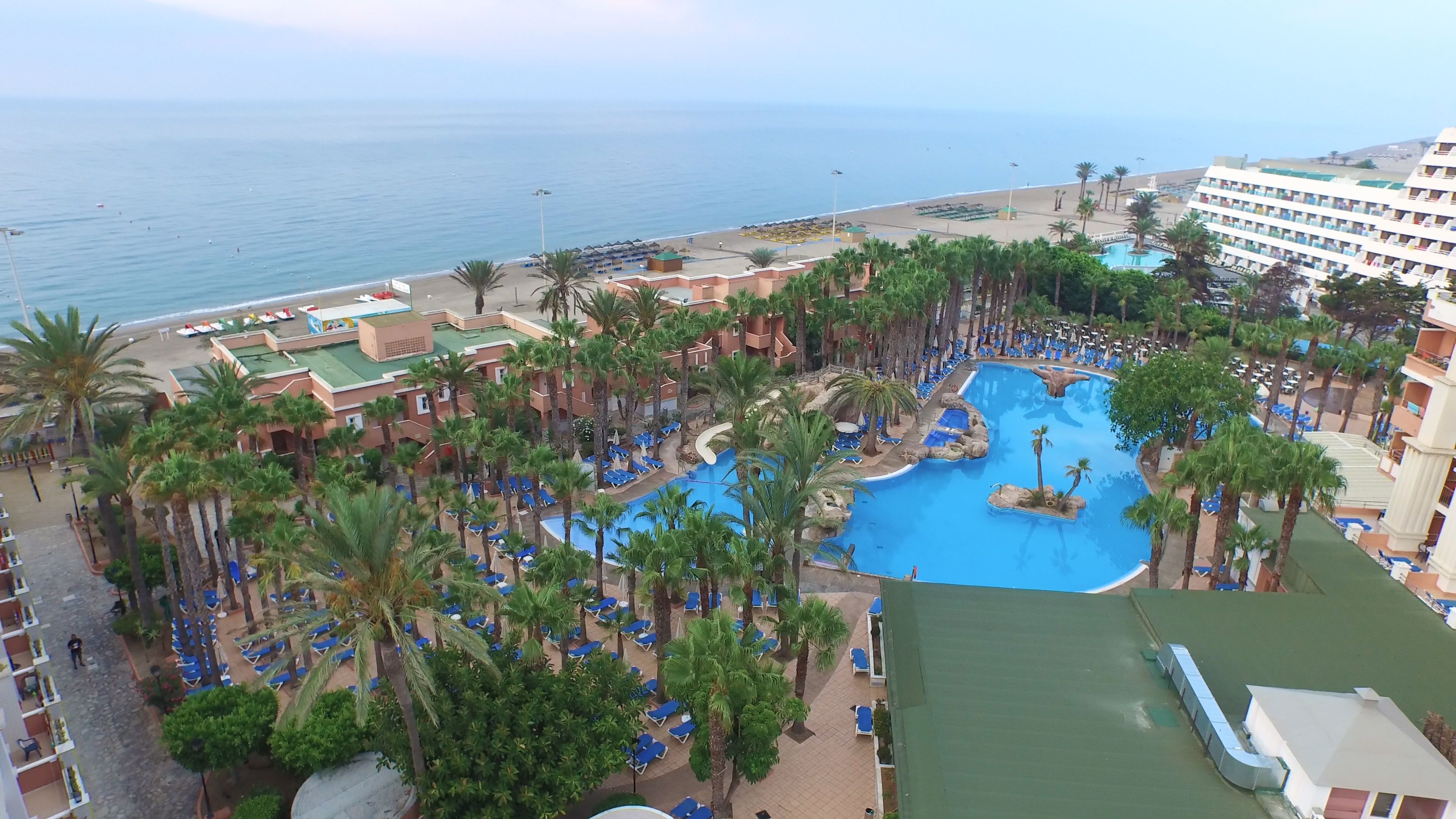 Un resort con una amplia piscina, palmeras y una playa.