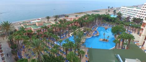 A resort with a large pool, palm trees, and a beach.