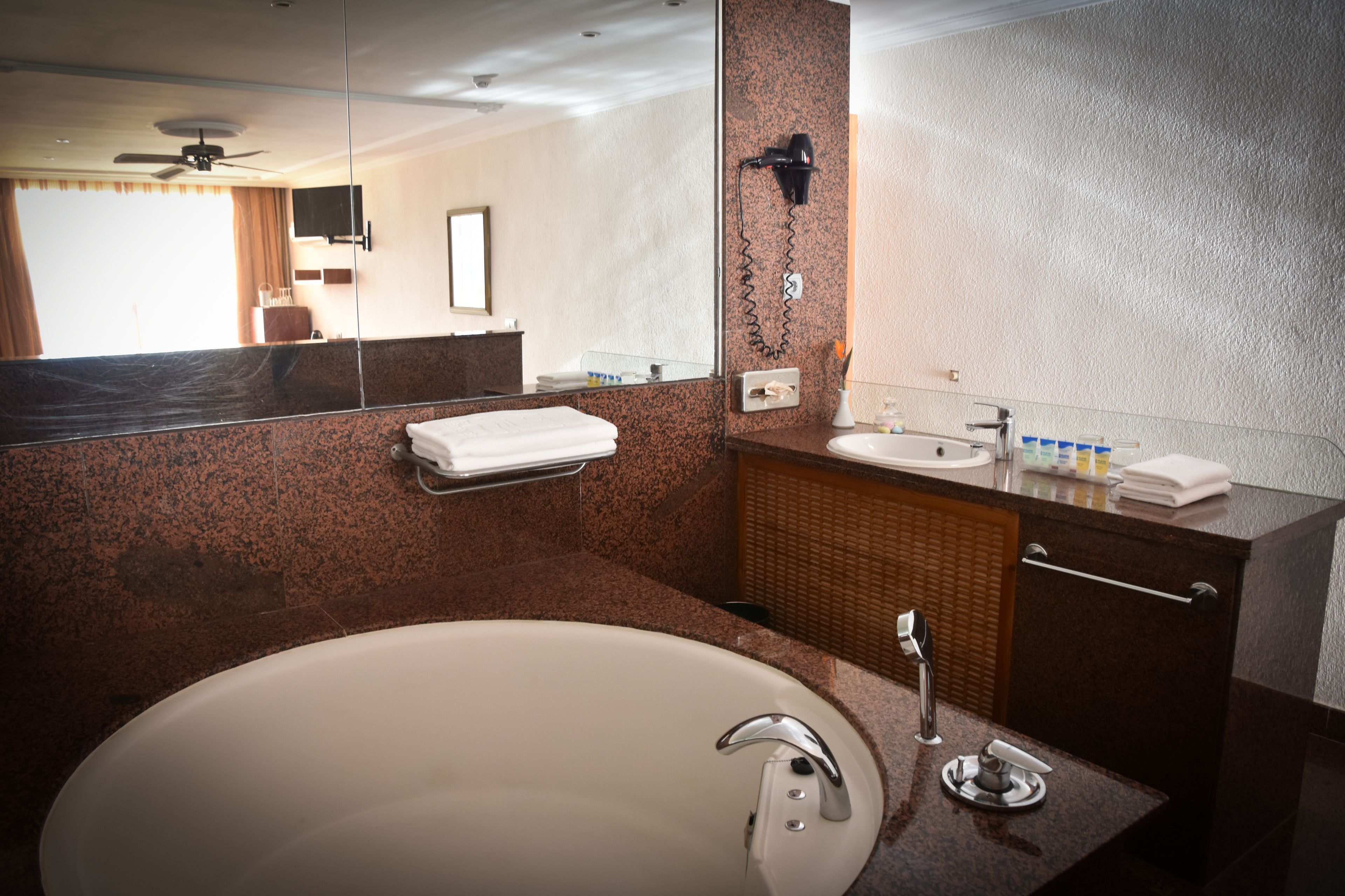 A modern bathroom with a large bathtub, a sink, and a mirror.