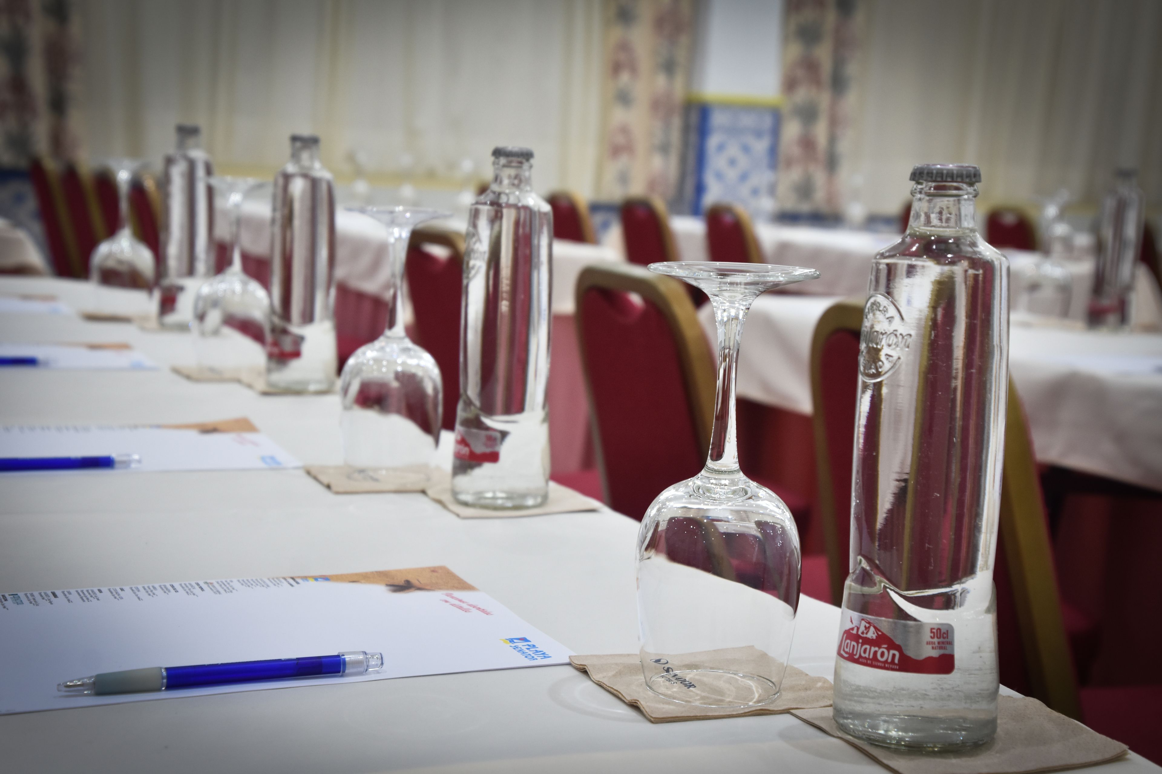 A conference room with tables set up with water bottles, glasses, and papers.
