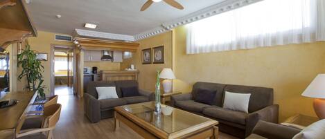 A spacious living area with a ceiling fan, two sofas, a coffee table, and a dining area with chairs.