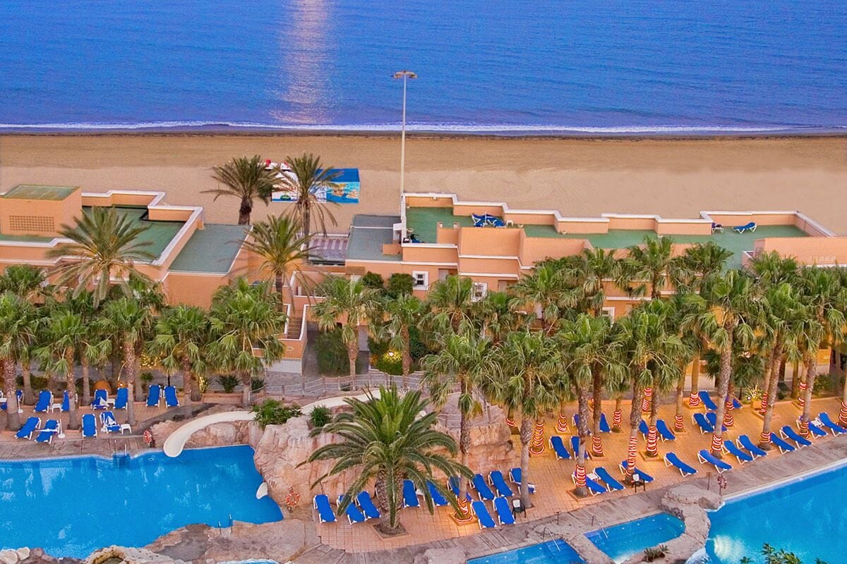 A resort with multiple swimming pools, palm trees, and beach access.