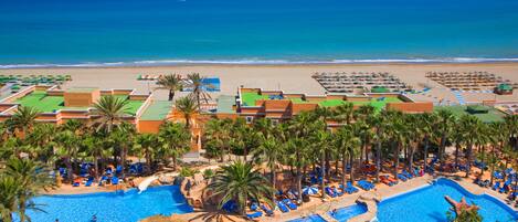 A resort with multiple swimming pools, a beach, and a view of the ocean.