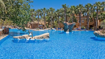 Relax by the pool surrounded by palm trees and a scenic rocky landscape.