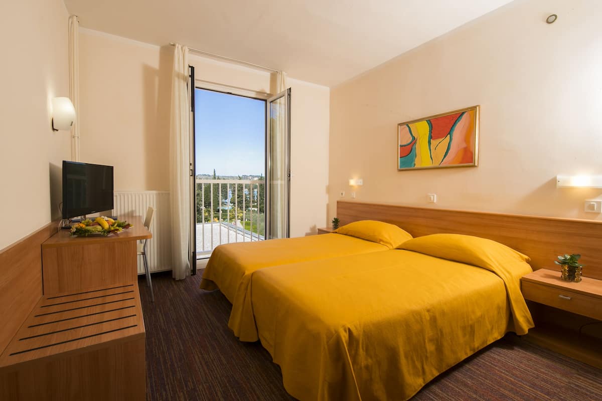 A hotel room with a bed, a TV, a desk, and a balcony with a view.