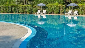A swimming pool with lounge chairs and umbrellas, surrounded by greenery. - Hotel Salinera - Sava Hotels & Resorts (Piran)