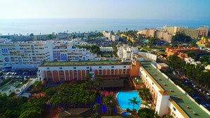 Un hotel con varias construcciones, piscina y vistas al mar.