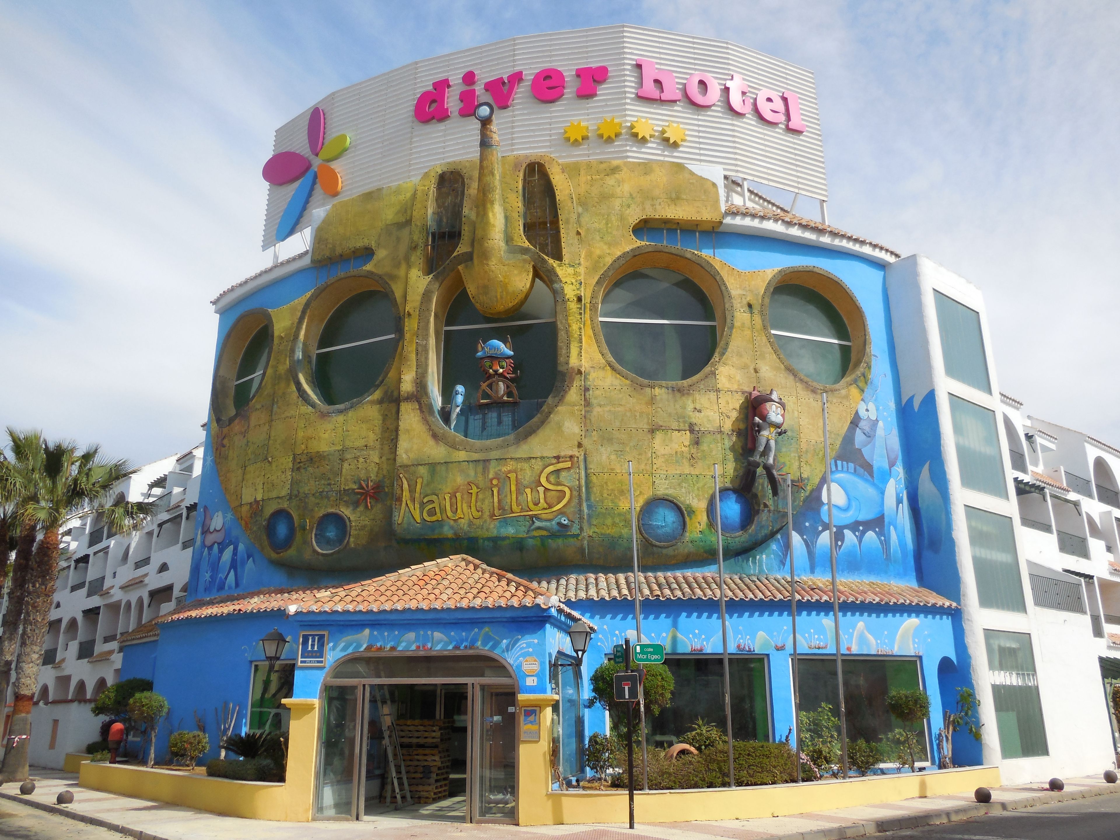 Un edificio con una fachada singular inspirada en la náutica, que incluye amplias ventanas circulares y un llamativo letrero 'Nautilus'.