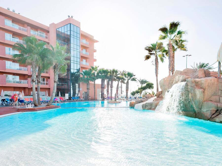 Una piscina cubierta, una piscina al aire libre, sombrillas, tumbonas