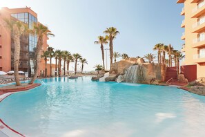 A swimming pool with palm trees, a waterfall, and modern buildings. - Hotel Best Roquetas (Roquetas de Mar)