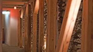 A corridor with wooden beams and stone walls, carpeted floor, and hanging light fixtures. - St. Olav Hotel (Tallinn)