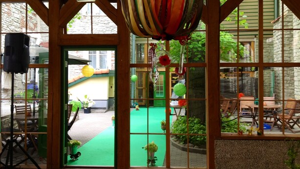 A room with a green carpet, wooden beams, and a large window with a view of the outside. - St. Olav Hotel (Tallinn)