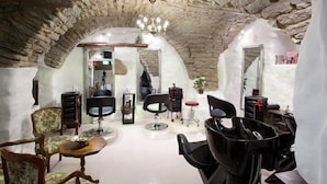 A salon with stone arches, multiple hairdressing chairs, and a mirror. - St. Olav Hotel (Tallinn)