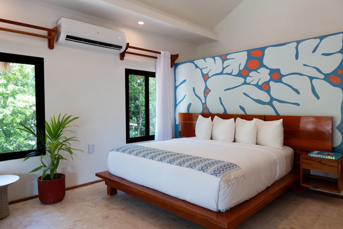 Ein Schlafzimmer mit einem großen Bett, einem Blumentopf, einem Nachttisch und einer Wand mit Blumenmuster.
