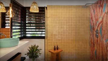 Un baño con un lavamanos grande, una ducha con diseño de mosaico floral y un taburete de madera con artículos de aseo.
