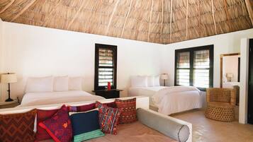A hotel room with two beds, a thatched roof, and a woven chair.