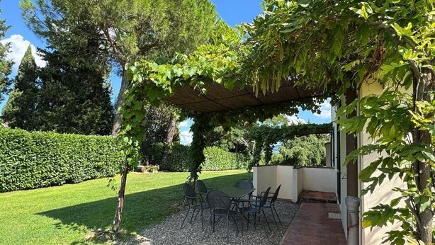 Eine Terrasse mit Sitzgelegenheiten im Freien, einer Pergola und einem Gartenbereich.