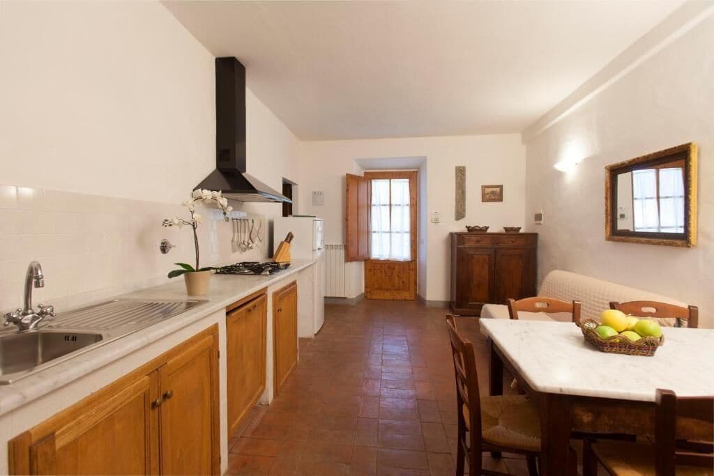 A kitchen with a sink, stove, and cabinets, leading to a dining area with a table and chairs.