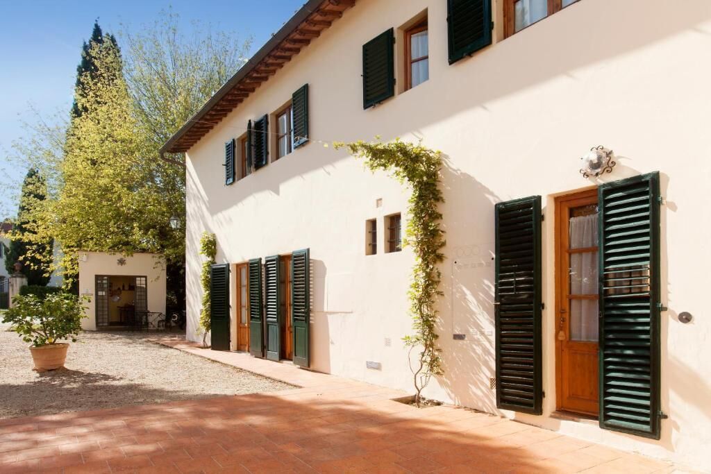 Un edificio con patio, contraventanas verdes y una planta en maceta.