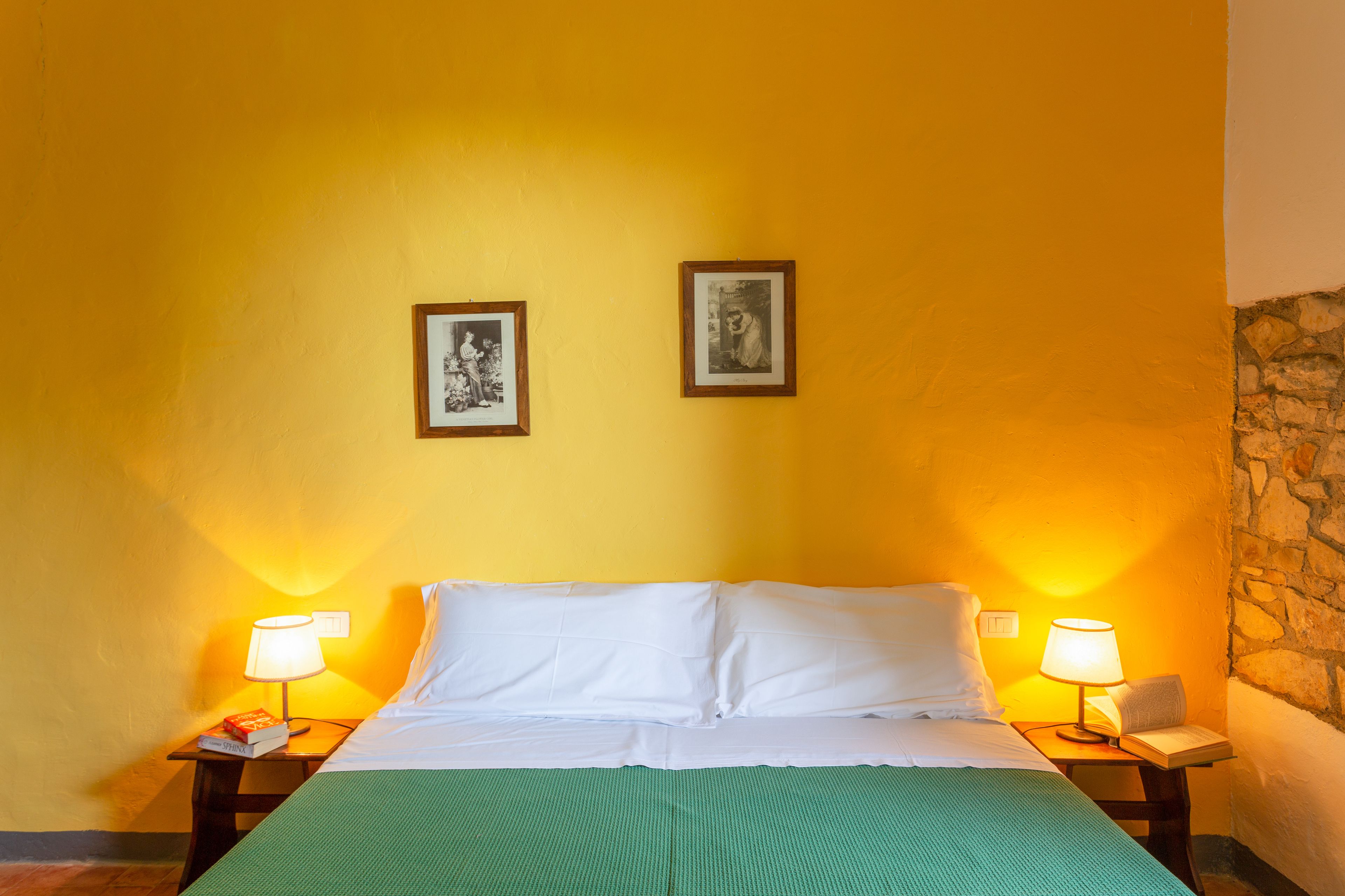 Ein Hotelzimmer mit einem Bett, zwei Nachttischlampen und zwei gerahmten Bildern an der Wand.
