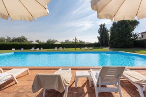 Una piscina al aire libre, sombrillas, tumbonas
