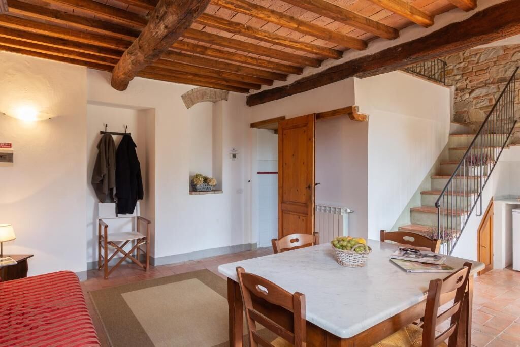 Una stanza con soffitto in legno, un tavolo da pranzo con sedie, un letto e una scala.