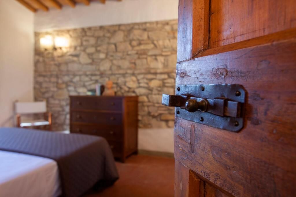 Une chambre avec un mur en pierre, des meubles en bois et un lit.