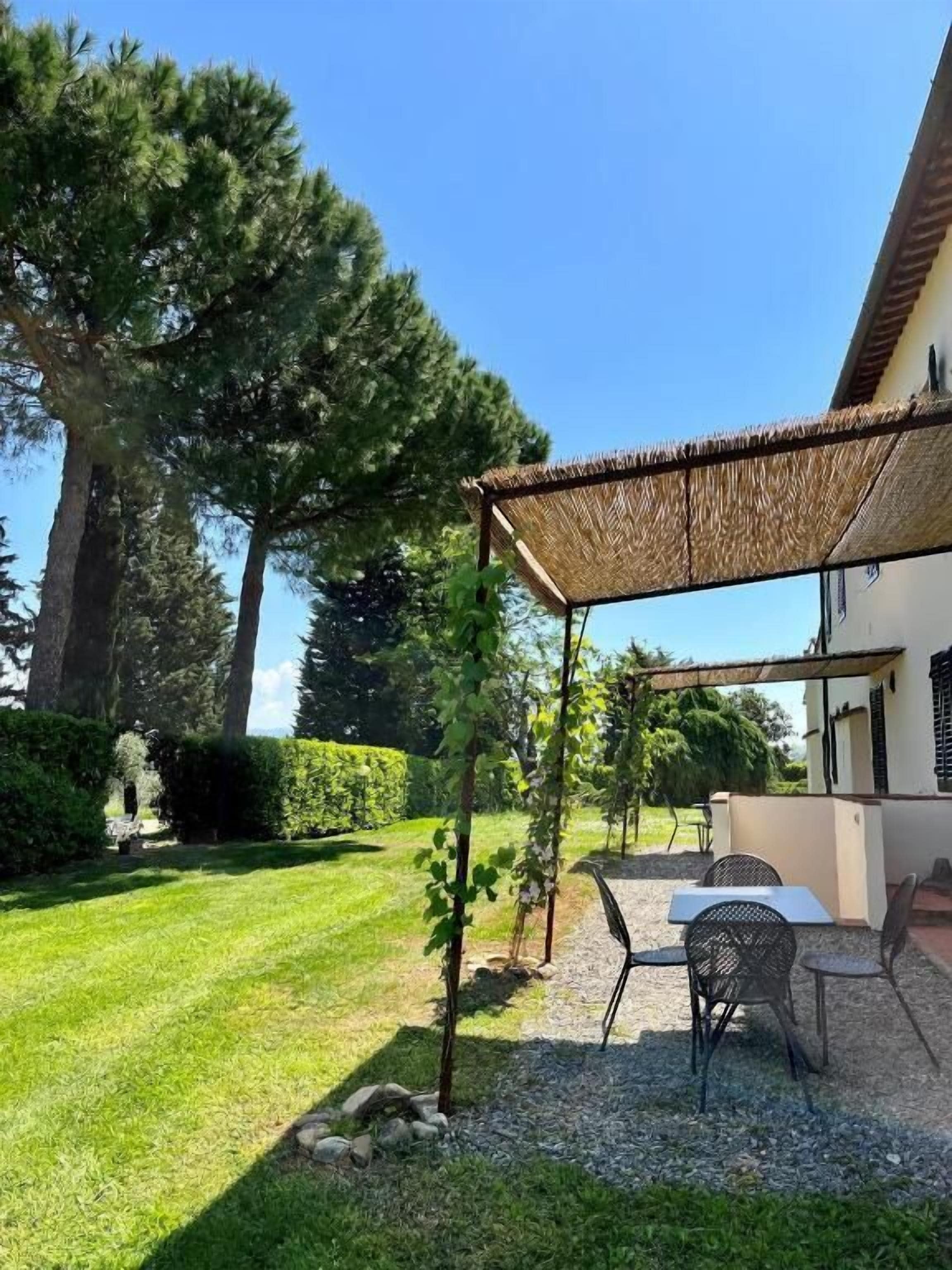 A patio with a thatched roof, outdoor seating, and a well-maintained lawn.