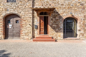 A stone building with a wooden door, a small window, and a metal gate.