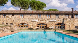 A stone building with a swimming pool, arched windows, and outdoor seating. - Fattoria Pratale (Barberino Tavarnelle)