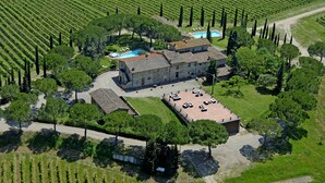 A large stone building with a tiled roof, surrounded by vineyard rows, a swimming pool, and a parking area. - Fattoria Pratale (Barberino Tavarnelle)