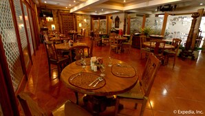 Un restaurant avec de nombreuses tables et chaises en bois, dont certaines sont dotées de sets de table.