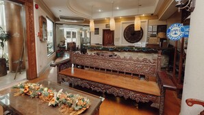 Un intérieur traditionnel avec des meubles en bois richement décorés, un comptoir d’accueil et un panneau indiquant la présence d’un téléphone public.