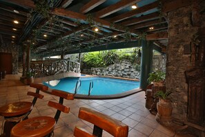 An indoor swimming pool with wooden benches and stone walls. - Crown Regency Residences - Cebu (Cebu City)