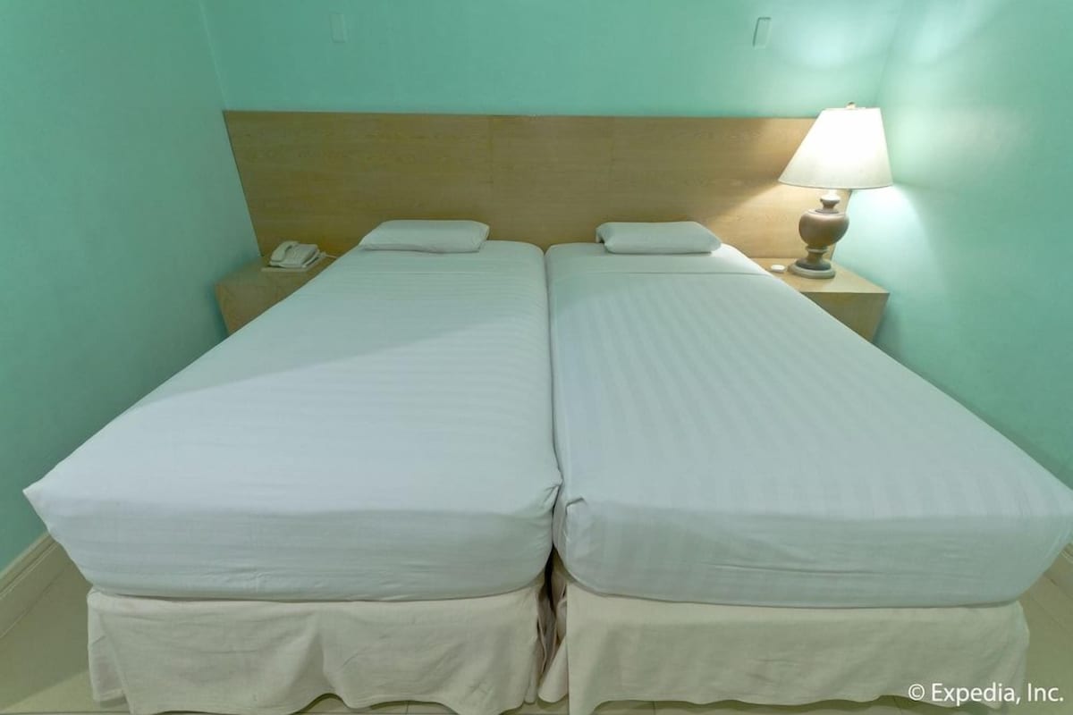 A twin room with two single beds, a nightstand with a lamp, and a phone.